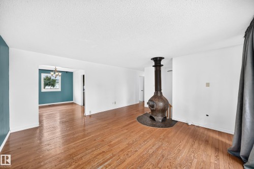 Wood-finish flooring, a free-standing solid fuel stove with a protective hearth, and a pass-through opening to an additional room - 11007 37 Avenue Nw, Edmonton, AB 