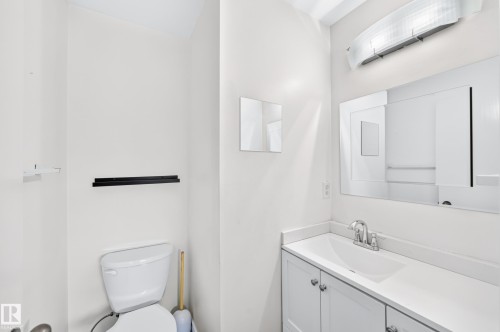 White vanity with cabinet storage, integrated sink, and chrome faucet - 11007 37 Avenue Nw, Edmonton, AB 