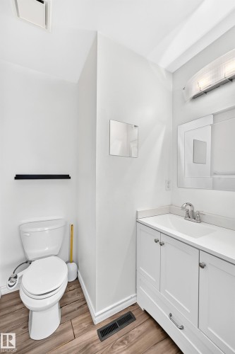 Wood-finish flooring with a white vanity featuring a single sink - 11007 37 Avenue Nw, Edmonton, AB 