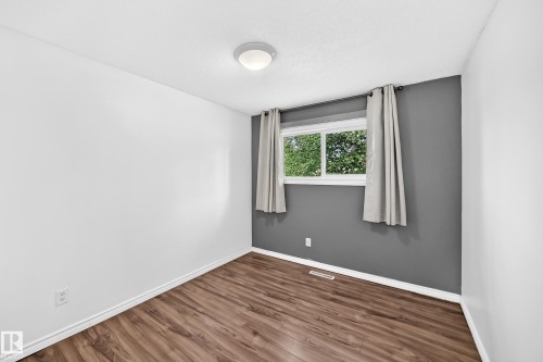 Room featuring wood-finish flooring, a window with natural light, and a ceiling-mounted light fixture - 11007 37 Avenue Nw, Edmonton, AB 