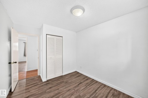 Wood-finish flooring, white walls, louvered closet doors, and flush-mount ceiling lighting - 11007 37 Avenue Nw, Edmonton, AB 