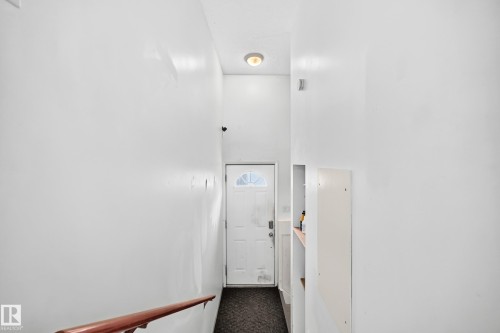 Entryway featuring a white door with an arched window, a built-in shelf, and a ceiling-mounted light fixture - 11007 37 Avenue Nw, Edmonton, AB 