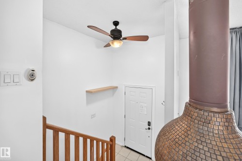 Wood-finish ceiling fan with integrated lighting, wood-finish railing, white paneled door, and a built-in floating shelf - 11007 37 Avenue Nw, Edmonton, AB 