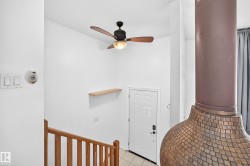Wood-finish ceiling fan with integrated lighting, wood-finish railing, white paneled door, and a built-in floating shelf - 