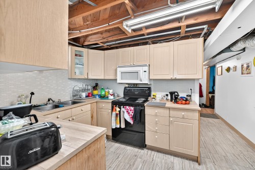 Full kitchen featuring light wood-finish cabinetry, tile flooring, and integrated appliances - 11007 37 Avenue Nw, Edmonton, AB 