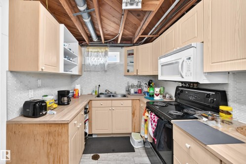 Kitchen featuring wood-finish cabinetry, wood-finish countertops, stainless steel double basin sink, and a tiled backsplash - 11007 37 Avenue Nw, Edmonton, AB 