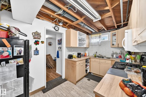 Galley-style kitchen with light wood-finish cabinetry, a double basin sink, and a four-burner electric range - 11007 37 Avenue Nw, Edmonton, AB 