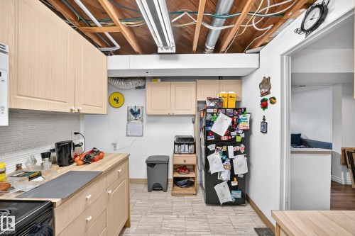 Light wood-finish cabinetry with white knobs, wood-finish countertops, and a white mosaic tile backsplash - 11007 37 Avenue Nw, Edmonton, AB 