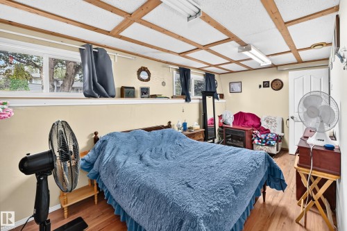Wood-finish flooring, wood beam ceiling, white paneled door, and a low-set window - 11007 37 Avenue Nw, Edmonton, AB 