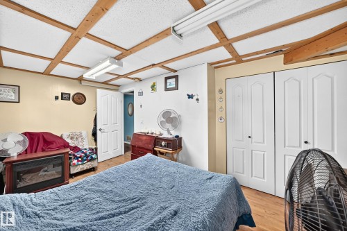 Wood-finish flooring, two sets of bi-fold closet doors, white interior door, exposed wood ceiling beams, and recessed lighting - 11007 37 Avenue Nw, Edmonton, AB 