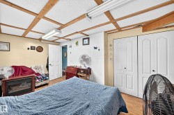 Wood-finish flooring, two sets of bi-fold closet doors, white interior door, exposed wood ceiling beams, and recessed lighting - 