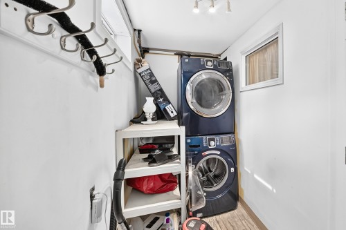 Stacked laundry appliances, overhead lighting, wood-finish flooring, and a white framed window - 11007 37 Avenue Nw, Edmonton, AB 