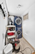 Stacked laundry appliances, overhead track lighting, wood-finish flooring, and a single window - 