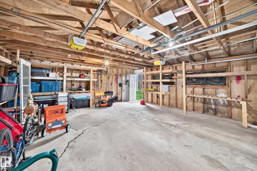 Expansive garage featuring open wood framing, concrete flooring, and built-in wood shelving units - 11007 37 Avenue Nw, Edmonton, AB 