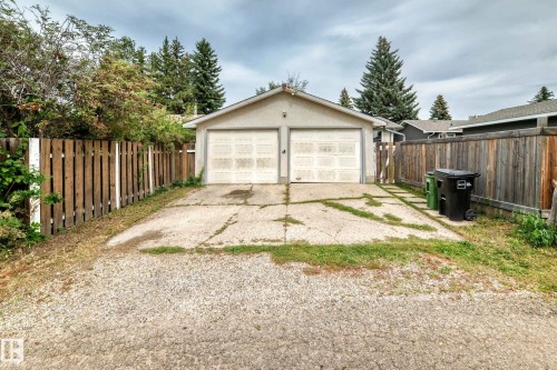 Detached two-car garage with overhead doors, concrete driveway, and gravel parking area - 11007 37 Avenue Nw, Edmonton, AB 