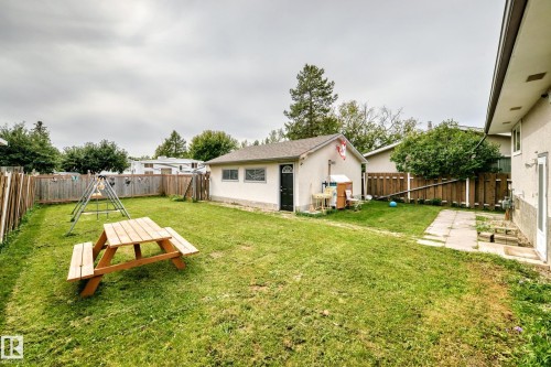 Expansive grass lawn with perimeter fencing, a detached auxiliary structure, and a patio stone pathway - 11007 37 Avenue Nw, Edmonton, AB 