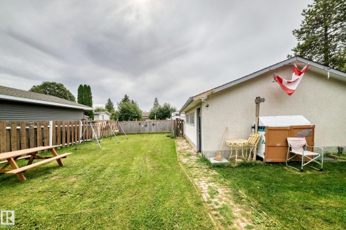 Expansive lawn area with perimeter fencing, a side entrance, and a brick pathway - 11007 37 Avenue Nw, Edmonton, AB 