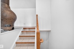 Stone brick fireplace with a dark hearth, wood-finish handrail, and tiled stairs with wood-finish risers - 