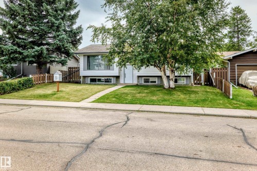 White siding exterior with a contrasting gray trim, front yard with a manicured lawn, concrete pathway, and mature trees - 11007 37 Avenue Nw, Edmonton, AB 