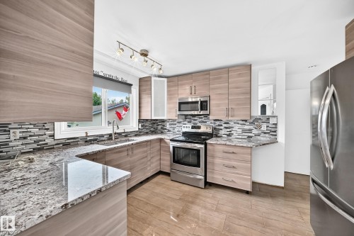 Modern kitchen featuring wood-finish cabinetry, stainless steel appliances, a mosaic tile backsplash, and light-toned countertops - 11007 37 Avenue Nw, Edmonton, AB 