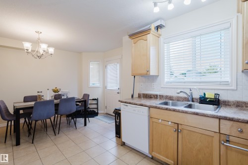 Kitchen featuring wood-finish cabinetry, stainless steel double sink, and light-colored countertops - 10332 161 Street Nw, Edmonton, AB 