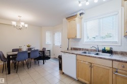 Kitchen featuring wood-finish cabinetry, stainless steel double sink, and light-colored countertops - 