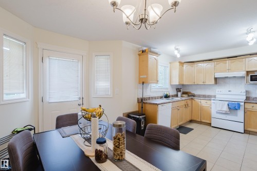 Kitchen and dining area featuring light wood-finish cabinetry, tile flooring, a built-in dishwasher, and a white oven - 10332 161 Street Nw, Edmonton, AB 