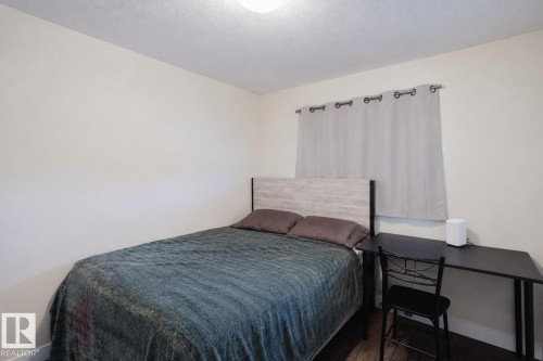 Hardwood-style flooring, neutral wall paint, and a window with curtain rod - 10332 161 Street Nw, Edmonton, AB 