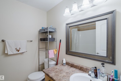 Vanity with a speckled countertop and integrated sink, framed mirror, and four-light vanity fixture - 10332 161 Street Nw, Edmonton, AB 