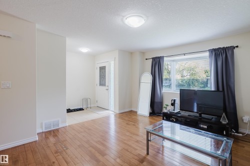 Hardwood flooring, front entry with decorative glass door, bay window, flush-mount lighting, and neutral wall finishes - 10332 161 Street Nw, Edmonton, AB 