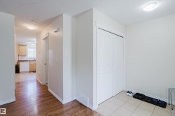 Warm wood-finish flooring, white walls, and a built-in closet with bi-fold doors - 