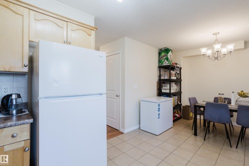 Kitchen featuring light wood-finish cabinetry, a white refrigerator, and a speckled countertop - 10332 161 Street Nw, Edmonton, AB 