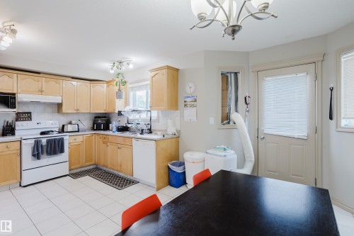 Kitchen featuring light wood-finish cabinetry, white tile flooring, white appliances, and a white tile backsplash - 10334 161 Street Nw, Edmonton, AB 