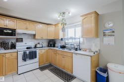 U-shaped kitchen featuring wood cabinetry, white tile flooring, white appliances, and a window above the sink - 