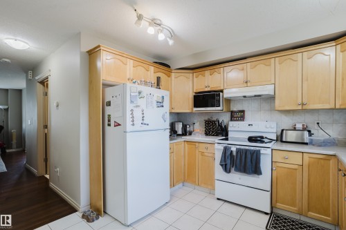 Light wood-finish cabinetry, white tile flooring, white appliances, and track lighting - 10334 161 Street Nw, Edmonton, AB 