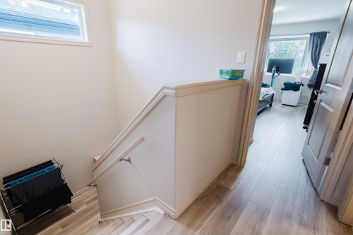 Wood-finish flooring throughout, featuring a staircase with a white painted handrail and a high-set window - 10334 161 Street Nw, Edmonton, AB 