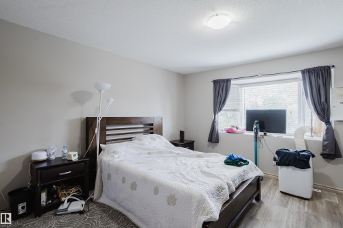 Neutral wall paint, wood-finish flooring, ceiling-mounted light fixture, window with blinds, and dark window treatments - 10334 161 Street Nw, Edmonton, AB 