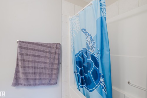 White tiled shower surround with an integrated white bathtub and a chrome grab bar - 10334 161 Street Nw, Edmonton, AB 
