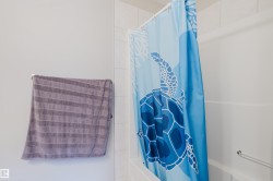White tiled shower surround with an integrated white bathtub and a chrome grab bar - 