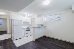 Kitchen featuring white cabinetry, white appliances, track lighting, and a breakfast bar - 