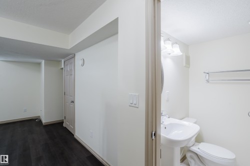 Pedestal sink, wall-mounted vanity lighting, and chrome towel bar in the bathroom - 10334 161 Street Nw, Edmonton, AB 