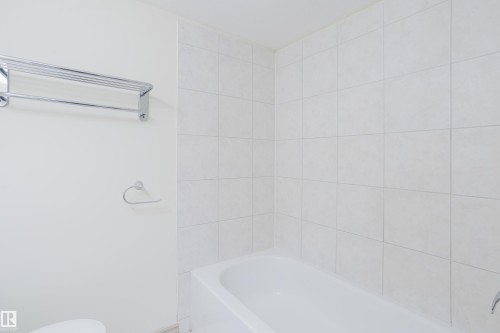 Integrated bathtub with white tile surround and chrome fixtures - 10334 161 Street Nw, Edmonton, AB 