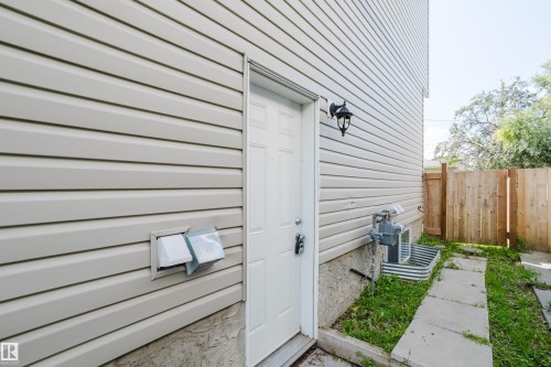 Light-toned siding exterior featuring a white entry door with an attached exterior light fixture - 10334 161 Street Nw, Edmonton, AB 