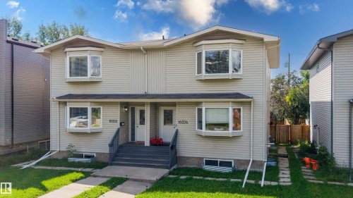 Duplex featuring light-colored siding, multiple bay windows, and individual front entrances - 10334 161 Street Nw, Edmonton, AB 