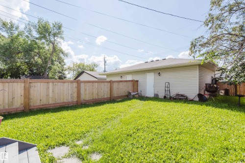 Expansive backyard with a lush lawn, privacy fence, and a detached structure featuring siding and exterior lighting - 10334 161 Street Nw, Edmonton, AB 