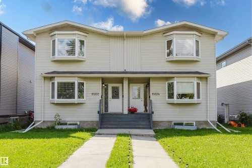 Duplex exterior featuring light-toned siding, two bay windows per unit, individual concrete walkways, and distinct front entrances with steps - 10334 161 Street Nw, Edmonton, AB 