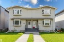 Duplex exterior featuring light-toned siding, two bay windows per unit, individual concrete walkways, and distinct front entrances with steps - 10334 161 Street Nw, Edmonton, AB 