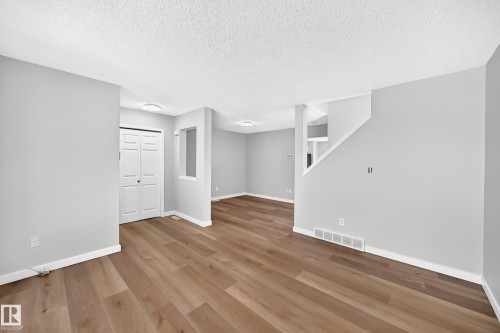 Spacious room featuring wood-finish flooring, light grey walls, and white baseboards - 203 84 Street Sw, Edmonton, AB - Indoor Photo Showing Other Room