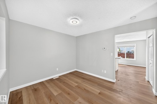 Bright room featuring wood-finish flooring, light gray walls, white trim, and a contemporary ceiling light fixture - 203 84 Street Sw, Edmonton, AB - Indoor Photo Showing Other Room