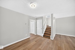 Expansive room featuring wood-finish flooring, light grey painted walls, white trim, and a contemporary ceiling light fixture - 